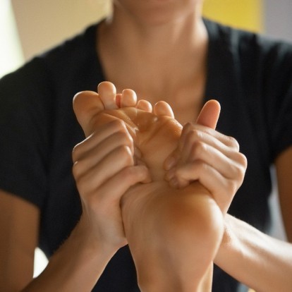 Close-up shot of masseuse doing relaxing foot massage made with forearms and cubits in cosmetology spa centre. Body care, skin care, wellness, wellbeing, beauty treatment concept.
